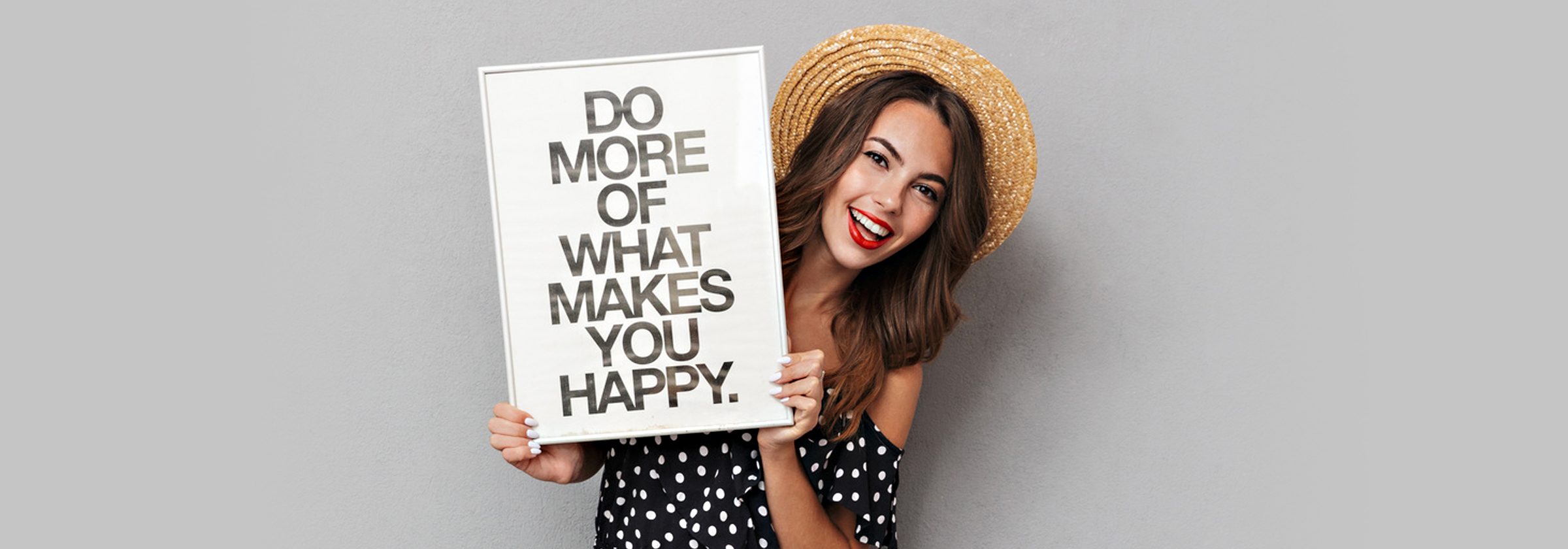 Junge Frau hält ein Schild hoch mit der Aufschrift " Do more of what makes you happy."